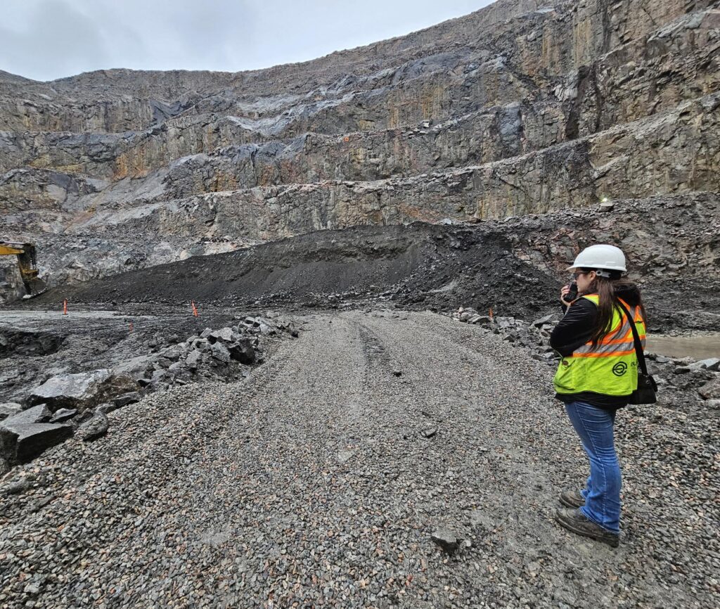 Female engineer in PPE talking on a walkie talkie in a mine pit